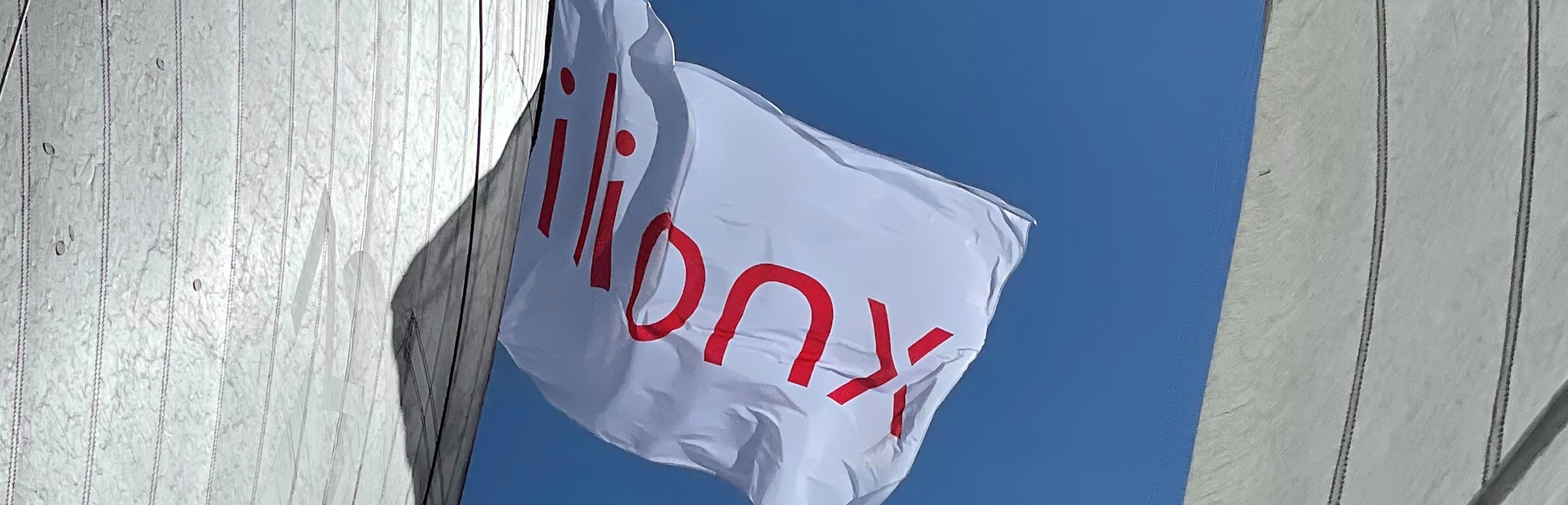 Vlag met het ilionx logo tegen een strak blauwe lucht