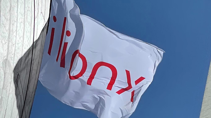 Vlag met het ilionx logo tegen een strak blauwe lucht