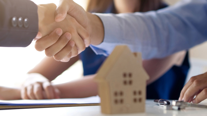 Afbeelding van handenschuddende mensen met een miniatuur huis op de voorgrond, ter ondersteuning bij klantverhaal Obvion